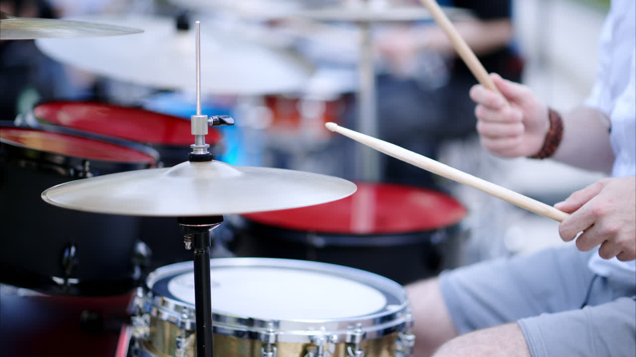 Close up of man playing red drums outside
