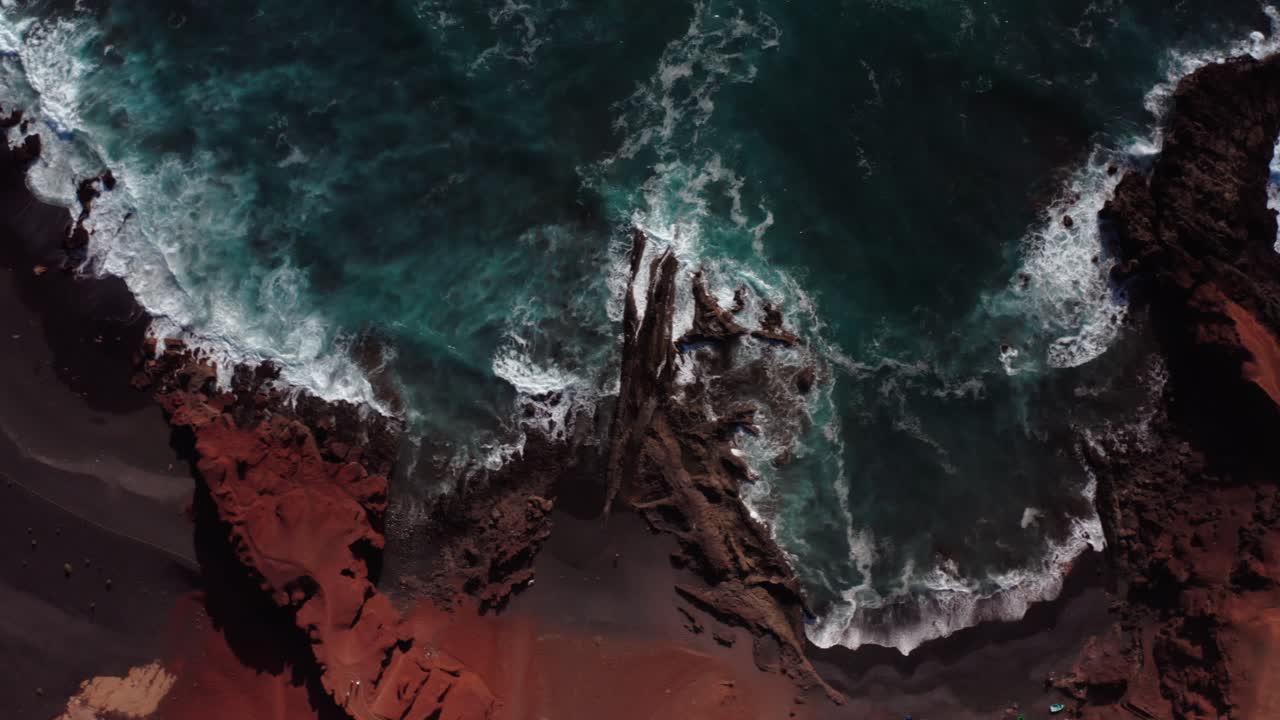 Letecký pohled dronu shora na oceánské vlny narážející na útesy na pobřeží Lanzarote, na Kanárských ostrovech.