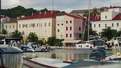 Boote-Schaukeln-Im-Vordergrund,-Während-Menschen-Die-Küstenpromenade-Von-Mali-Losinj-Erkunden