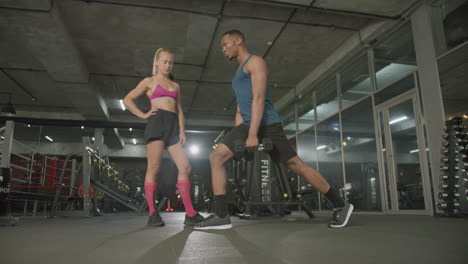 Lower-view-of-caucasian-female-monitor-and-an-athletic-african-american-man-in-the-gym.