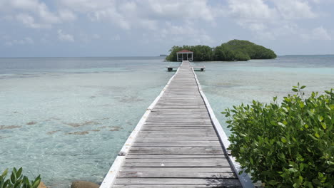 push in wide view of pier on belizean island in the caribbean