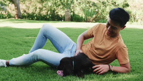 asian man playing with puppy on grass, enjoying sunny day outdoors, in park