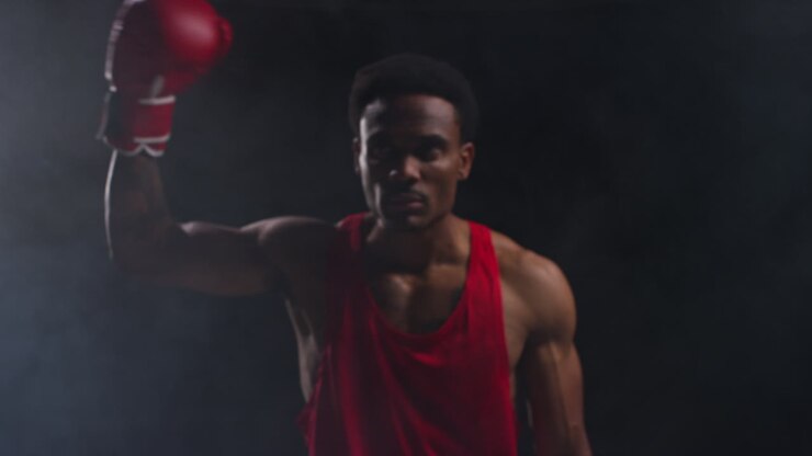 Ritratto di pugile che entra sul ring prima dell'inizio di un incontro di boxe, saluta i fan e si riscalda, con illuminazione a bassa chiave.