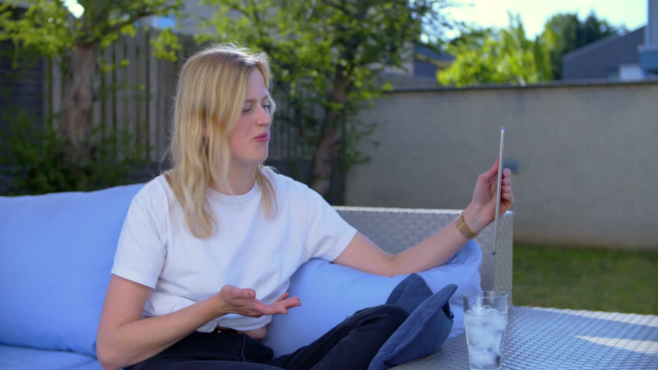 Girl video chatting with her friends on a lounge set