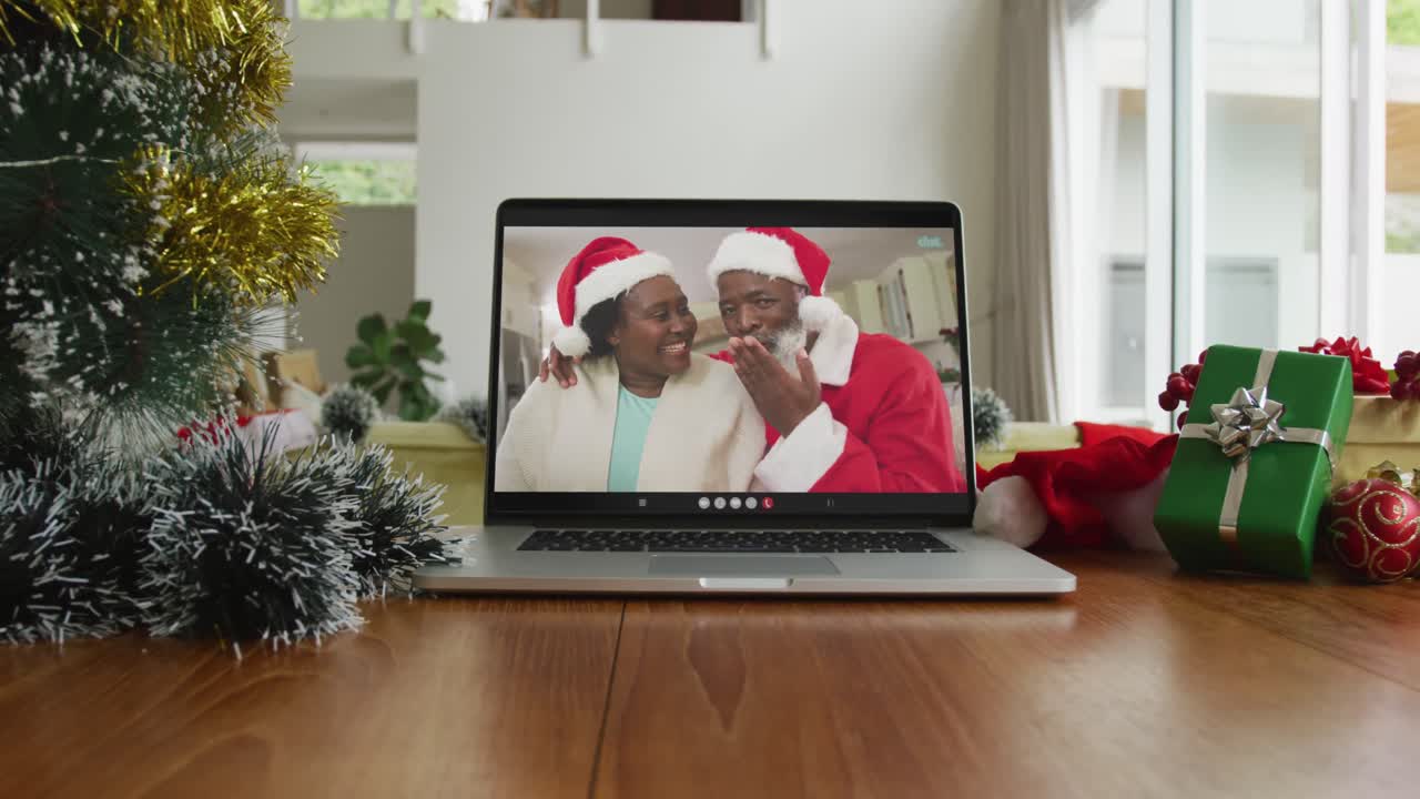 sonriente pareja afroamericana con sombreros de papá noel en una videollamada en una computadora portátil