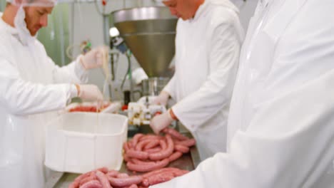 butchers packing sausages in container