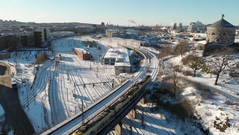 train passing by medieval tower, snow covered, gothenburg, sweden aerial