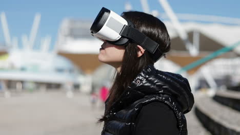 Side-view-of-young-dark-haired-woman-in-warm-black-waistcoat-wearing-virtual-reality-glasses