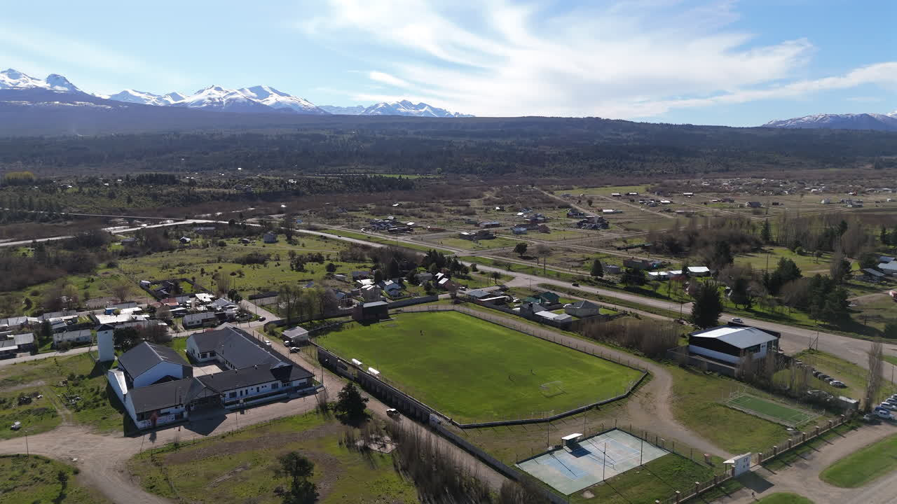 Aerial establishing fly Soccer stadium in wide rural Patagonian Location, mountain background landscape