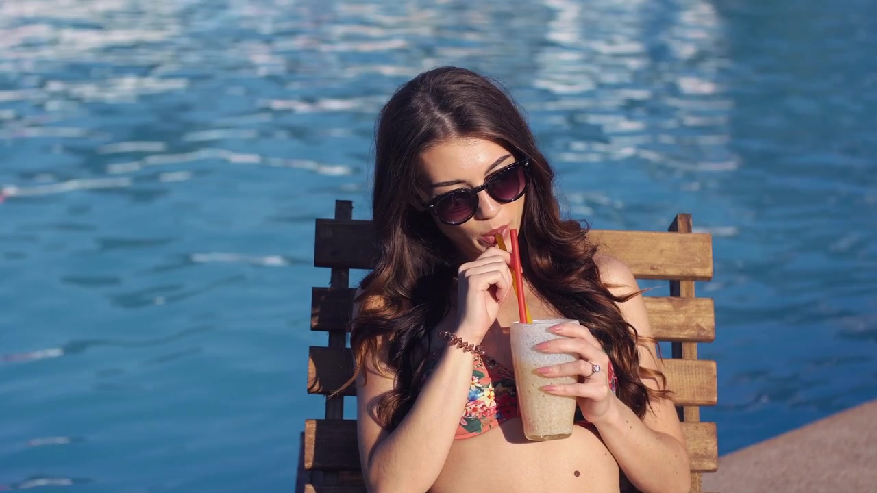 Young Woman Relaxing by the Pool with a Refreshing Drink