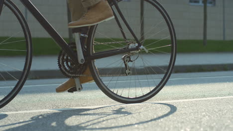 Close-up-of-bicycle-wheels-rolling-on-the-asphalt-road-while-man-rides-it-