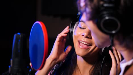 dos jóvenes cantantes interpretando su canción en un estudio de grabación. dúo de músicos profesionales grabando un nuevo álbum cd. hermosa pareja trabajando juntos. cámara lenta. 4k