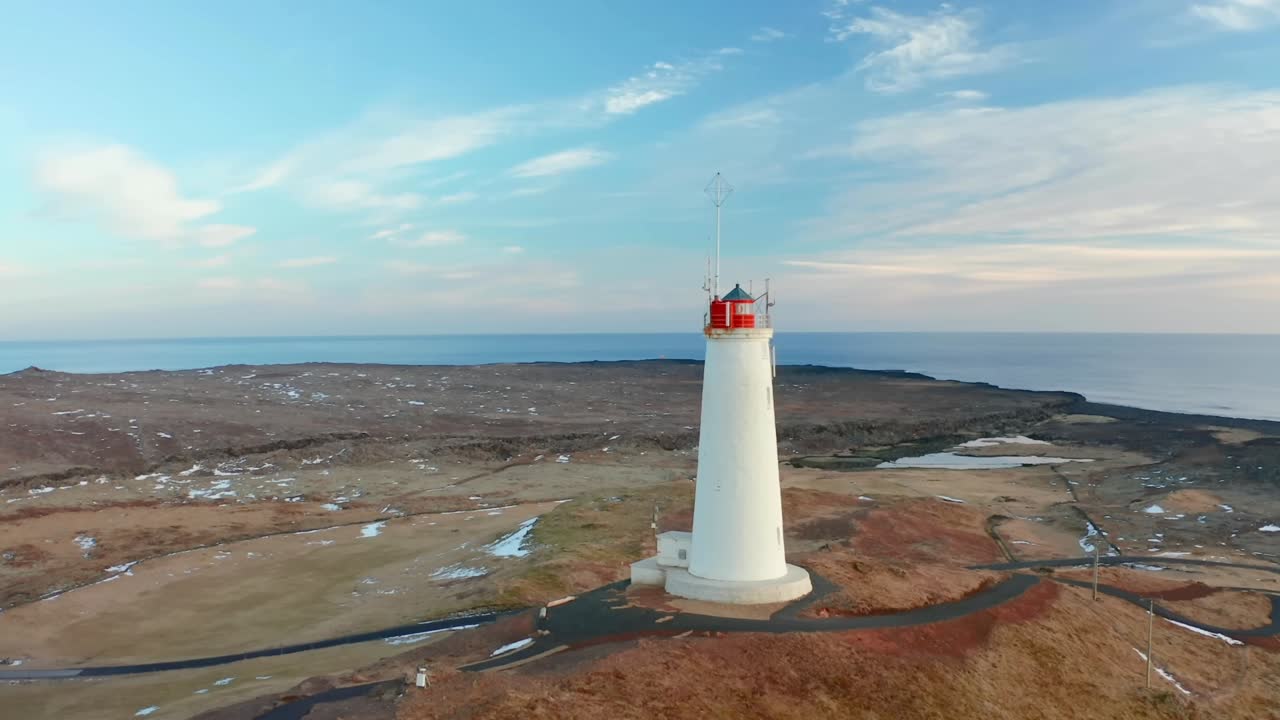 capturando impresionantes imágenes aéreas con un dron 4k, mostrando un faro en la cima de una colina con vistas al vasto mar nórdico y el extenso paisaje sin árboles de islandia