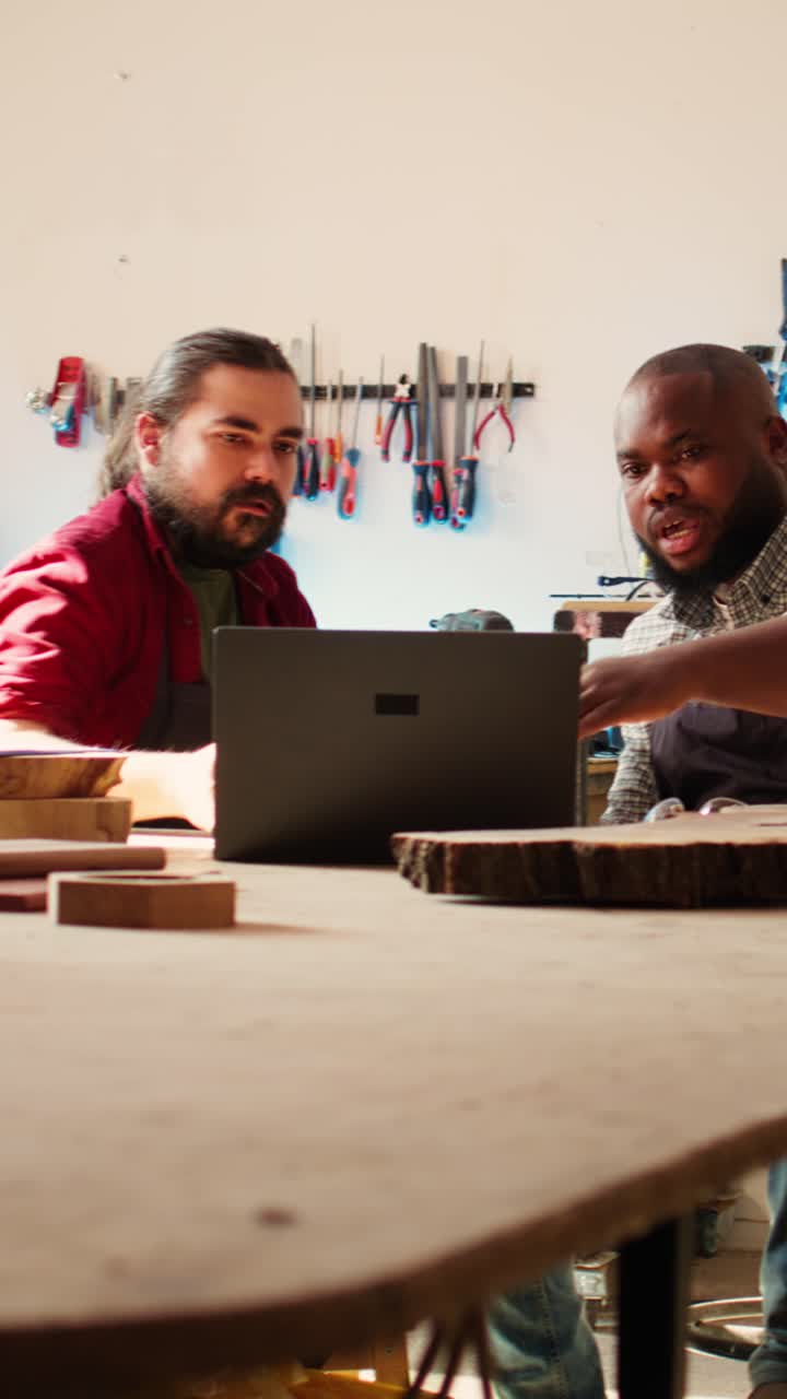 Two Woodworkers Collaborating on Laptop in a Workshop
