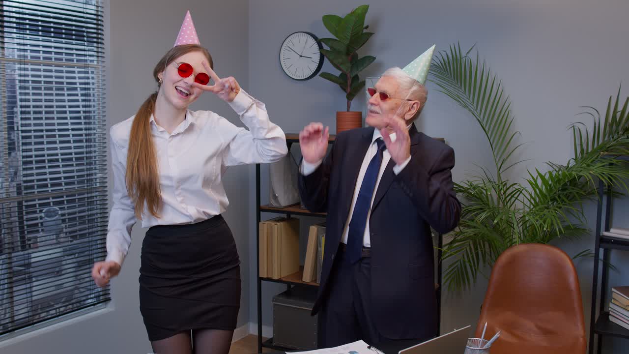 dos colegas alegres en trajes formales bailando el baile de la victoria, celebrando el éxito del proyecto de negocios