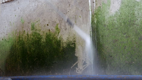 lavado con chorro de alta presión que limpia la sustancia verde de la superficie metálica