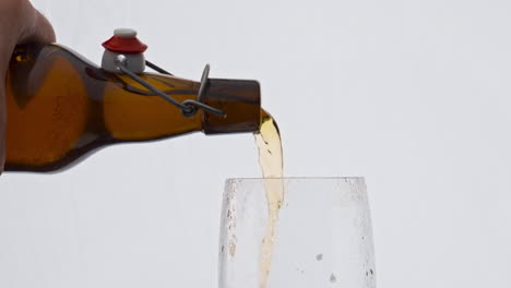 man hand pouring beer from bottle to glass in super slow motion close up.