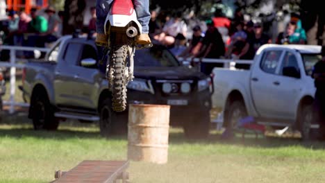 motorcyclist performs jump over barrels