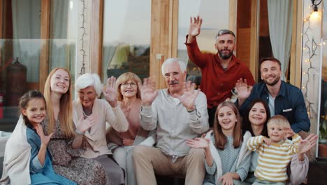 joyous caucasian family waving and posing for camera on terrace