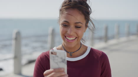 Porträt-Eines-Schönen-Jungen-Hispanischen-Mädchens,-Das-Sein-Smartphone-Benutzt-Und-Spaß-Daran-Hat,-SMS-Zu-Schreiben,-Online-Zu-Surfen-Und-Lachend-Nachrichten-An-Einem-Warmen-Sommerstrand-Zu-Lesen