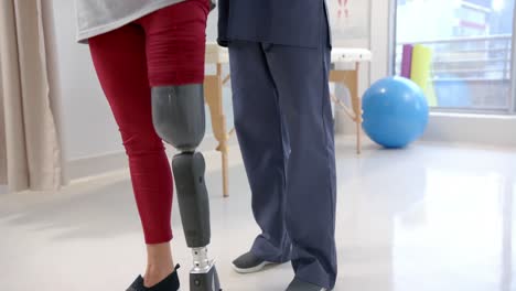 Caucasian-female-physiotherapist-and-female-senior-patient-with-prosthetic-leg-exercising