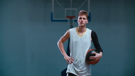 retrato de media longitud de un jugador de baloncesto caucásico posando con una pelota en el interior. 4k uhd