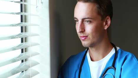 el médico de pie con los brazos cruzados y mirando por la ventana