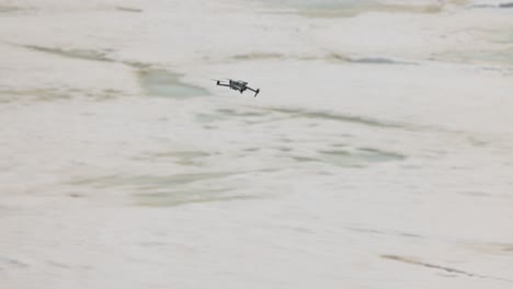 small drone quadcopter flies away quickly over empty winter landscape, no person