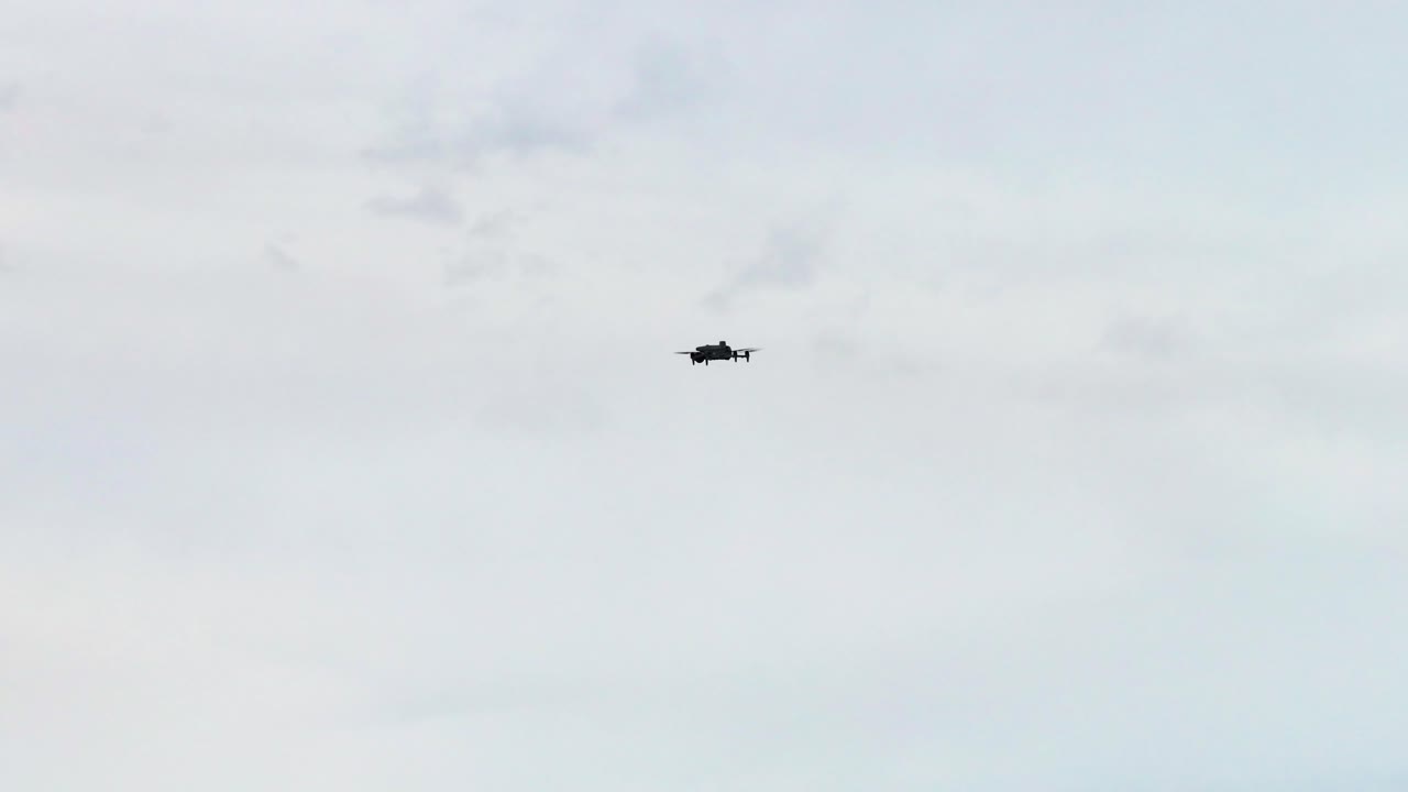 Unmanned drone silhouette flying against overcast cloudy sky, Czechia