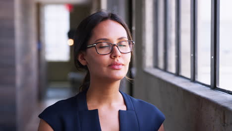 Young-businesswoman-wearing-glasses,-turns-to-camera,-smiles