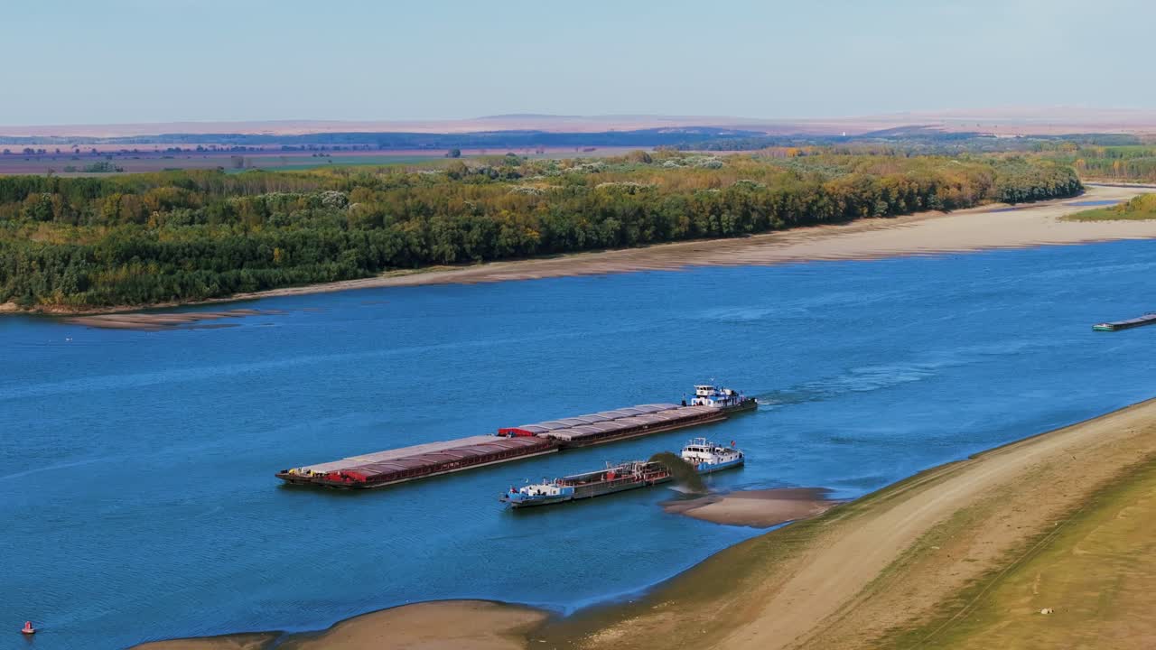 Aerial shot of a dredger unloading dredged sand on a big river, other ships passing by, sunny day
