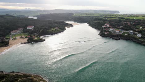 huge waves from the bay of biscay roll into the beautiful bay in spain's green sparsely populated province of cantabria on a partly cloudy day