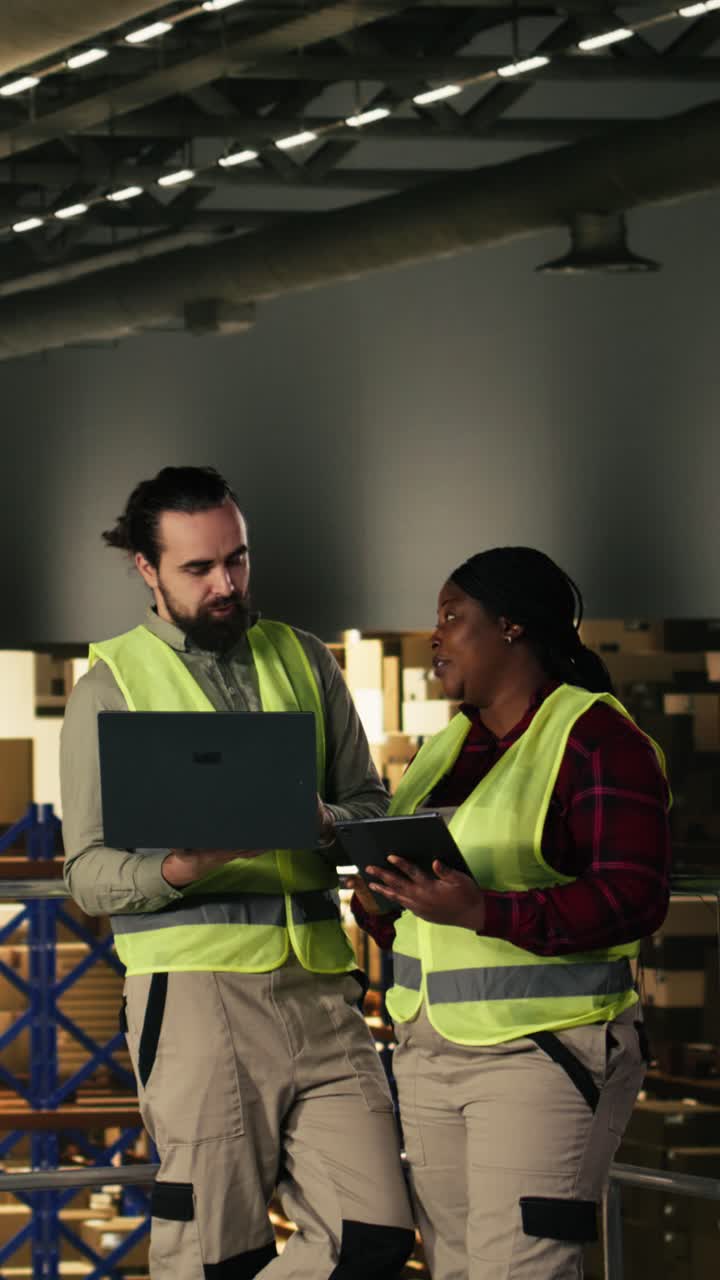 Vertical Video Two warehouse workers, laptop and tablet, distribution center, teamwork