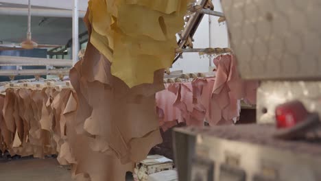 colour tanned animal hides on a automated drying rack in a leather factory, flashing light in foreground