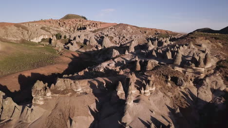 vista aérea de un paisaje surrealista con formaciones rocosas cónicas y terreno accidentado bajo un cielo despejado