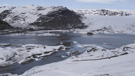 aerial establishing shot of the stunning icelandic lakes and snow-covered mountains