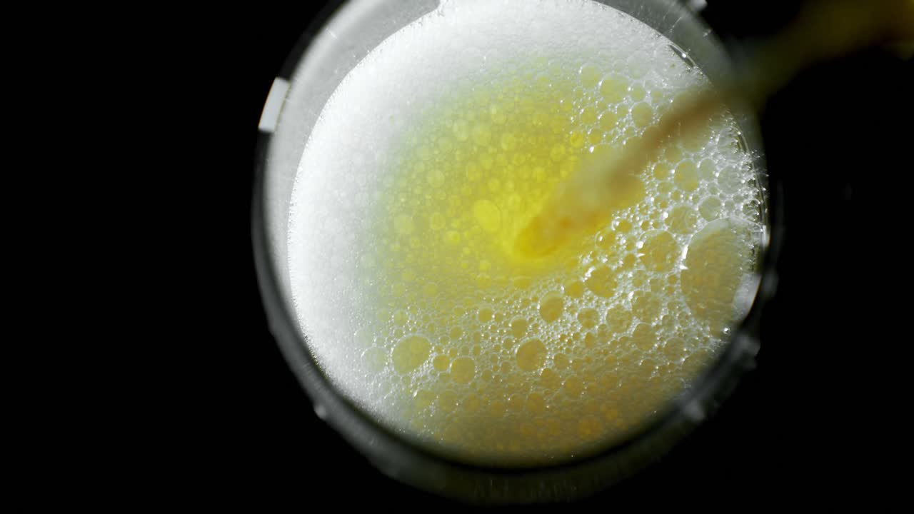 cerveza vertida en un vaso contra un fondo negro 4k