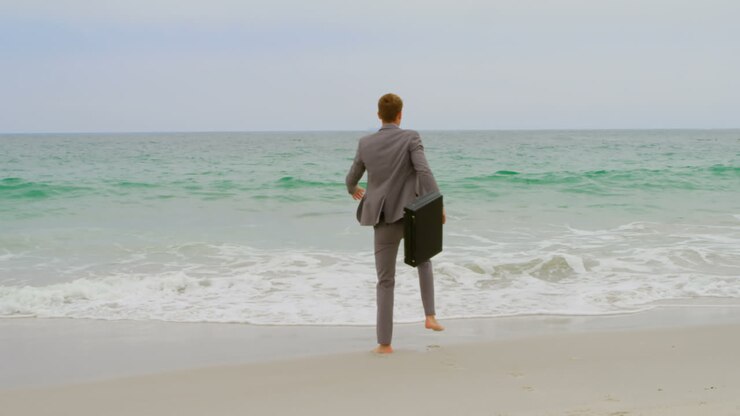 Rear view of Caucasian Businessman jumping with briefcase on the beach 4k