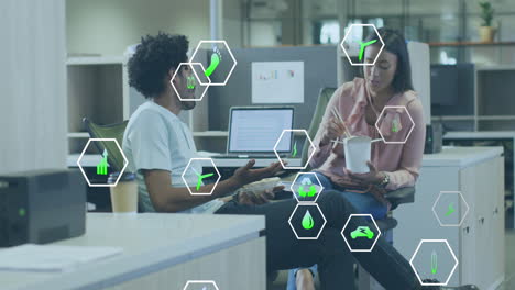 animation of icon in hexagons over diverse coworkers eating food and discussing on desk in office