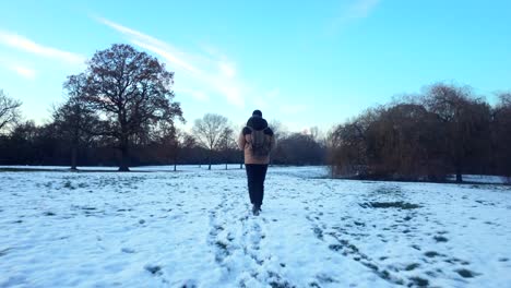 young man or teenage boy walking through heavy snow in nature landscape