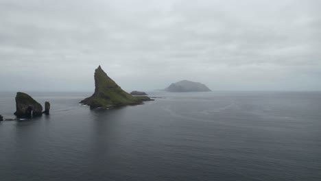 Plano-Amplio-De-Pilas-De-Mar-De-Drangarnir-Y-El-Islote-De-Tindholmur-Con-Mykines-Brumosos-En-El-Fondo