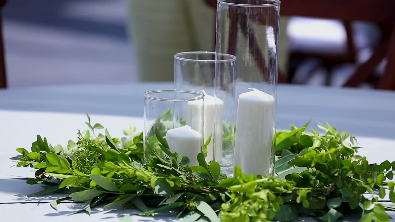 Candles in vases and decorative plants on the table for an open-air wedding