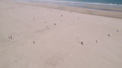 personas separadas disfrutando de un día soleado en la playa de arena, vista aérea