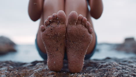 close up of sandy feet young woman sitting on beach barefoot enjoying summer vacation