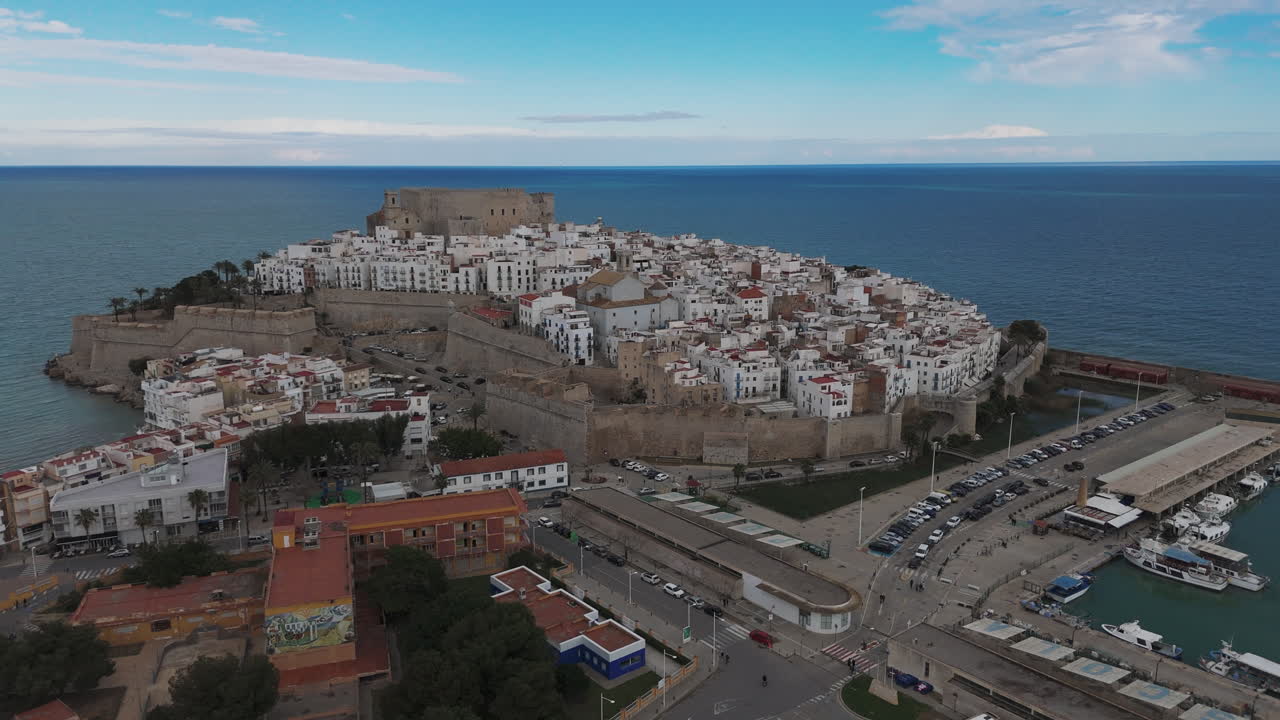 Aerial of Peniscola castle and old town with sea crashing against walls and harbor