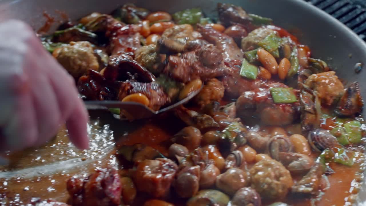 cocinero revuelve ingredientes para hacer paella española