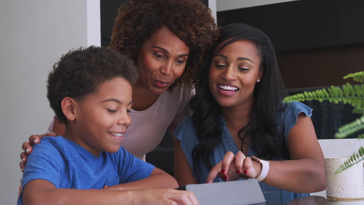 Nonna con la madre che aiutano il nipote a fare i compiti sul tablet digitale