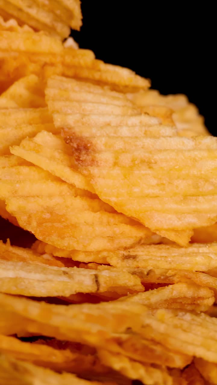 Golden ridged potato chips rotate smoothly, illuminated by soft studio lighting, with crisp texture detail