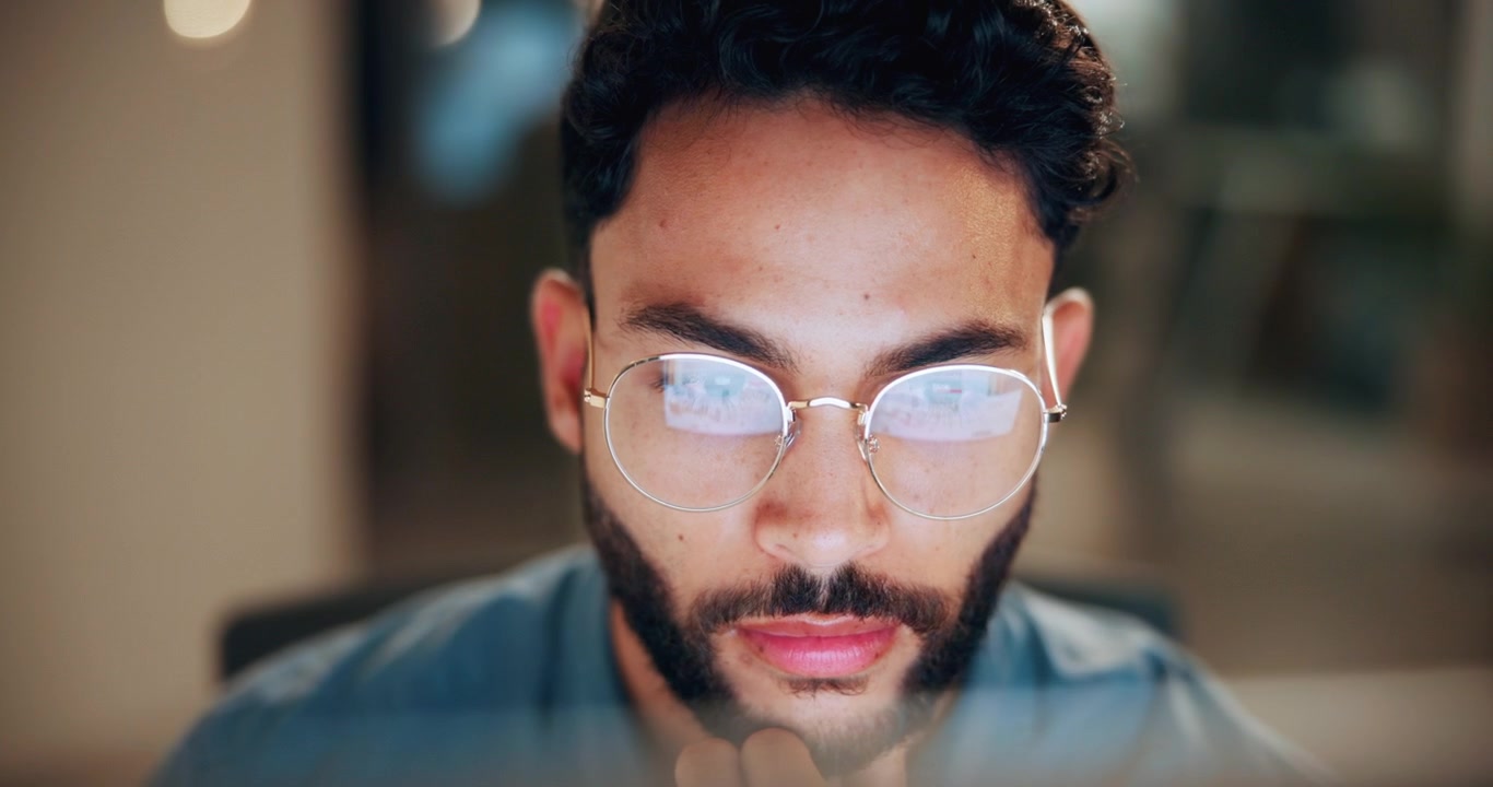 Giovane uomo concentrato mentre lavora al computer in ufficio di notte