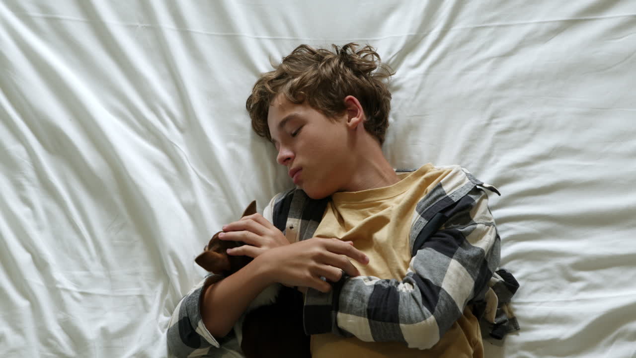 침대에 개와 함께 자고 있는 소년